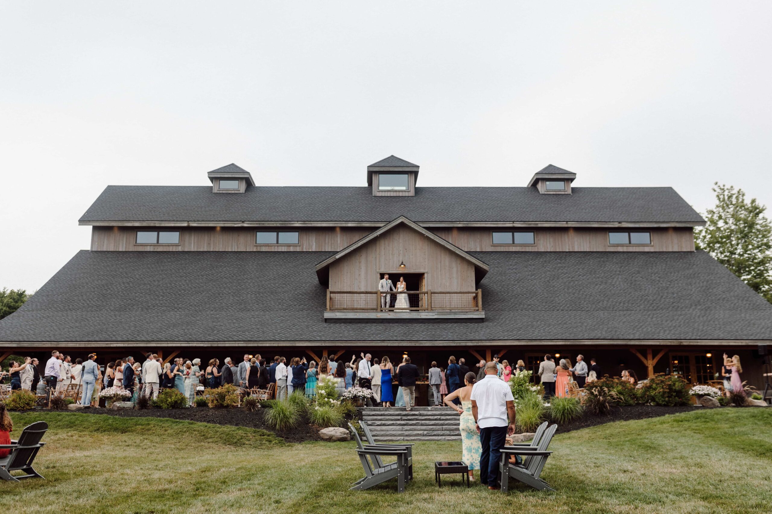 Couple waving on the balcony of Windham Manor reception venue to their guests during cocktail hour